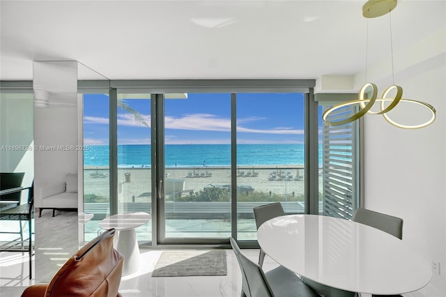 interior space featuring floor to ceiling windows, a water view, and a view of the beach