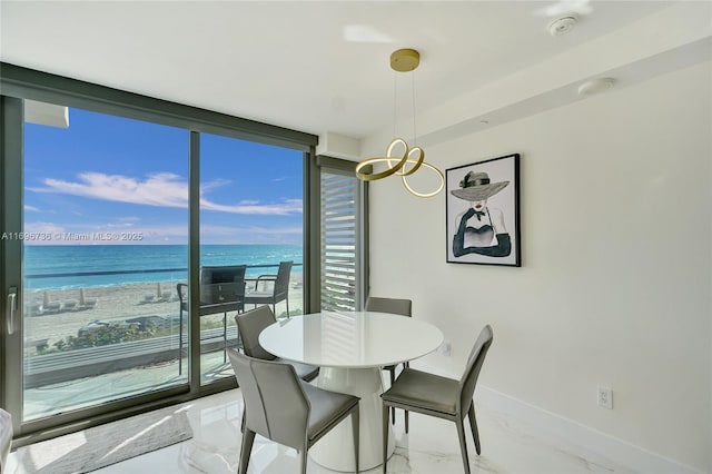 dining room with a water view, a wall of windows, plenty of natural light, and a beach view