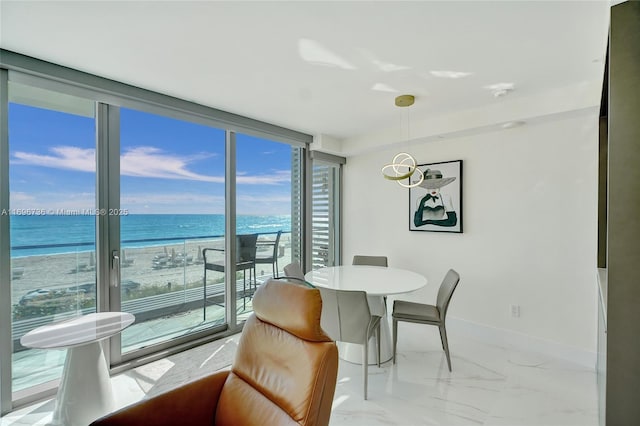 dining area featuring a water view, floor to ceiling windows, and a view of the beach