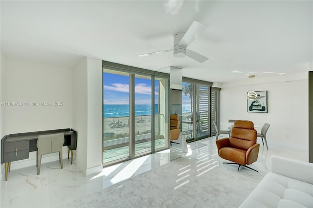 living room featuring ceiling fan, a water view, and expansive windows