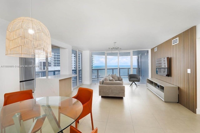 tiled living room featuring a water view, a notable chandelier, and a wall of windows