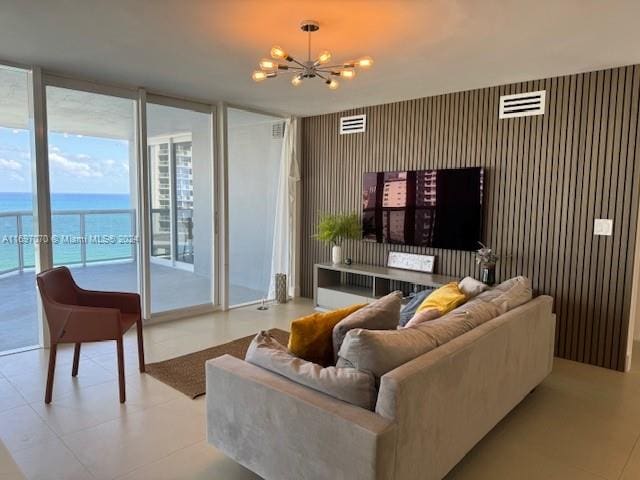 living room featuring floor to ceiling windows, wood walls, a water view, and a notable chandelier