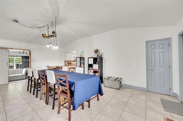 tiled dining space featuring a chandelier and vaulted ceiling