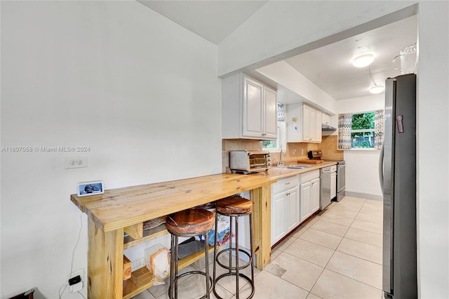 kitchen with white cabinets, sink, appliances with stainless steel finishes, tasteful backsplash, and light tile patterned flooring