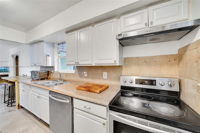 kitchen featuring sink, light tile patterned floors, tasteful backsplash, white cabinetry, and stainless steel appliances