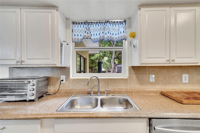 kitchen with backsplash, sink, white cabinets, and stainless steel dishwasher