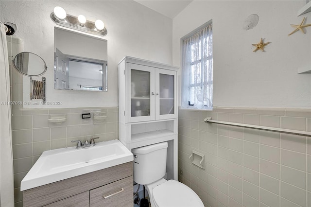 bathroom featuring vanity, toilet, and tile walls