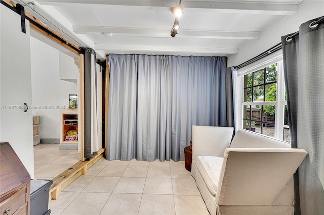 living area featuring light tile patterned floors, a barn door, and beam ceiling