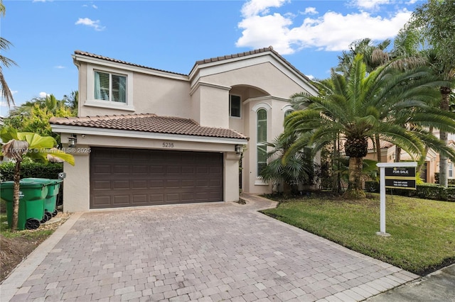 mediterranean / spanish home featuring a garage and a front yard