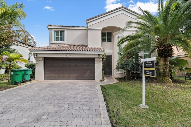 mediterranean / spanish house featuring a garage and a front lawn