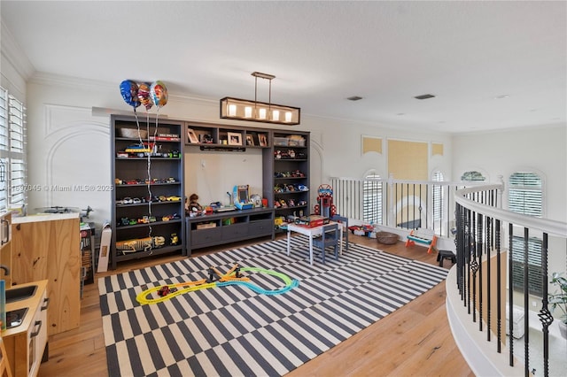 game room with hardwood / wood-style floors, crown molding, and plenty of natural light