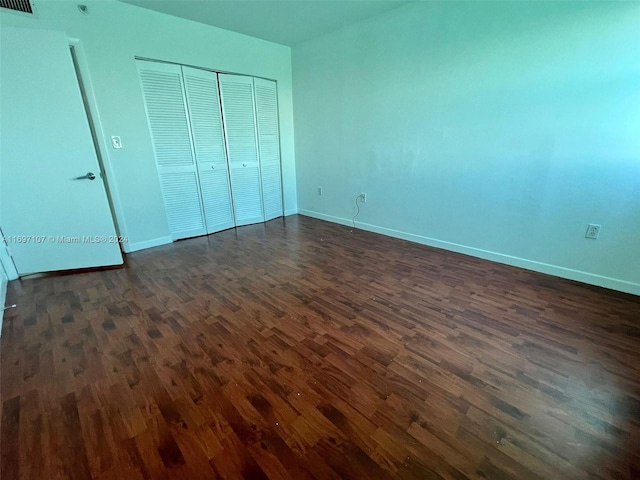 unfurnished bedroom with dark hardwood / wood-style flooring and a closet