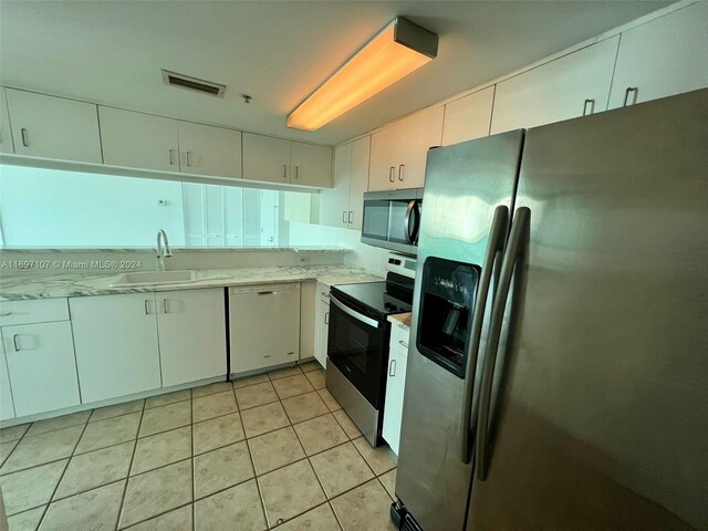 kitchen with light tile patterned floors, white cabinetry, sink, and appliances with stainless steel finishes