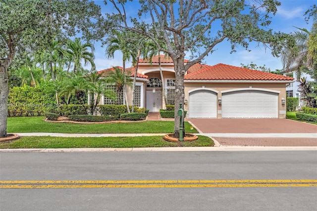 mediterranean / spanish-style home featuring a front yard and a garage