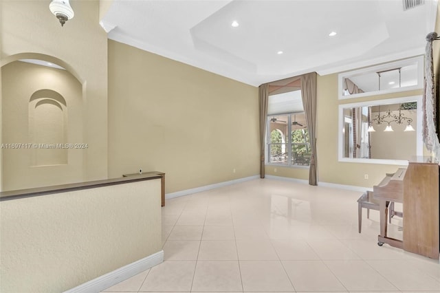 tiled empty room featuring a tray ceiling and crown molding