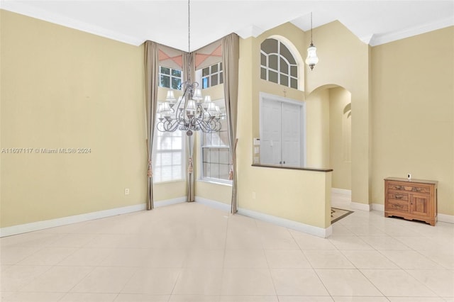 spare room with a notable chandelier, light tile patterned floors, ornamental molding, and a wealth of natural light