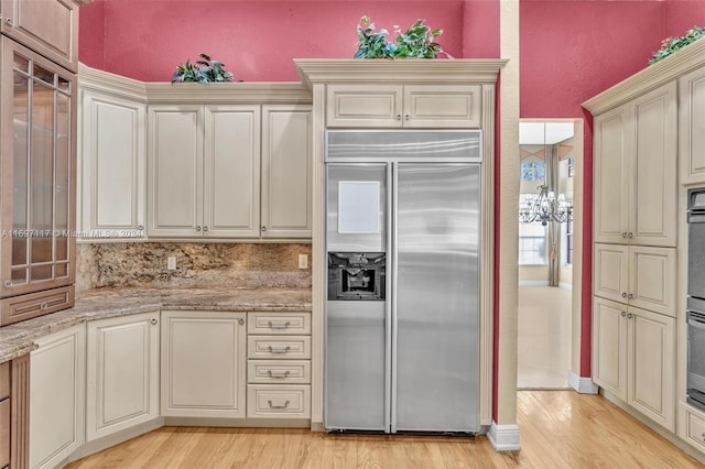 kitchen featuring light stone countertops, stainless steel appliances, light wood-type flooring, and cream cabinetry