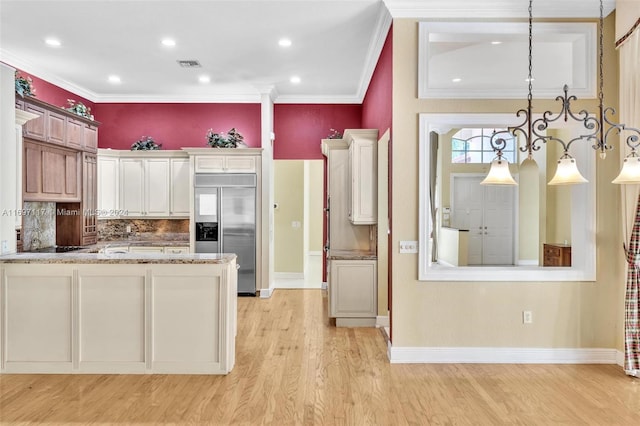 kitchen with light stone countertops, decorative light fixtures, stainless steel built in fridge, and light hardwood / wood-style flooring