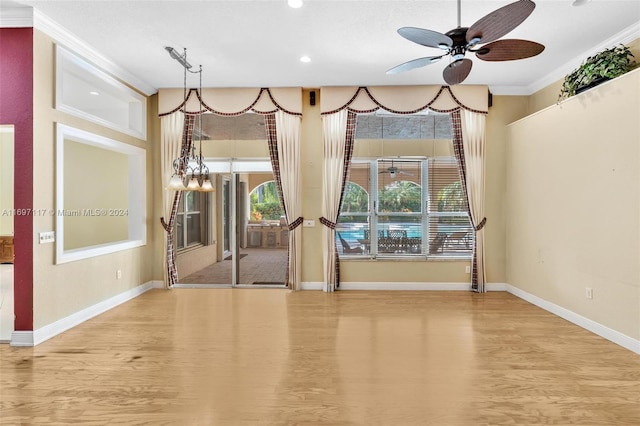 interior space with ceiling fan with notable chandelier, light hardwood / wood-style floors, and ornamental molding