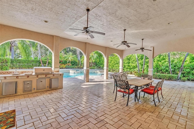 view of patio featuring area for grilling, ceiling fan, and an outdoor kitchen