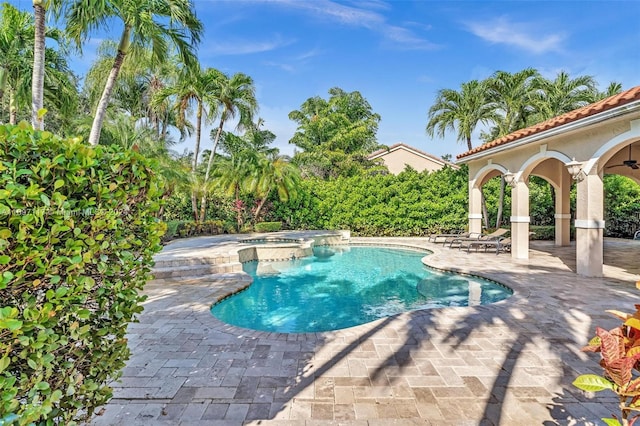 view of swimming pool with ceiling fan, an in ground hot tub, and a patio