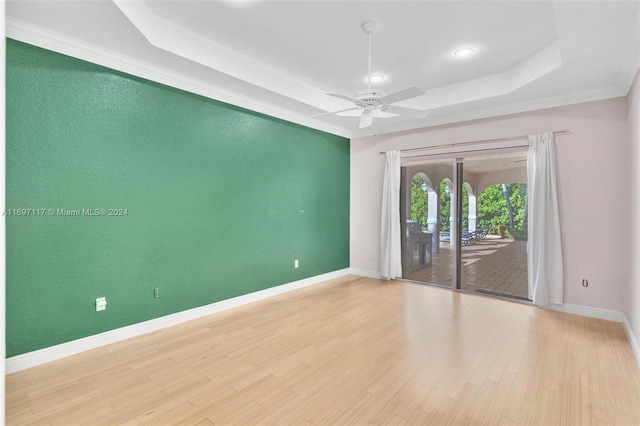 unfurnished room featuring a raised ceiling, crown molding, ceiling fan, and light hardwood / wood-style floors