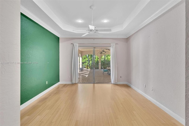 unfurnished room with a raised ceiling, light wood-type flooring, and ornamental molding