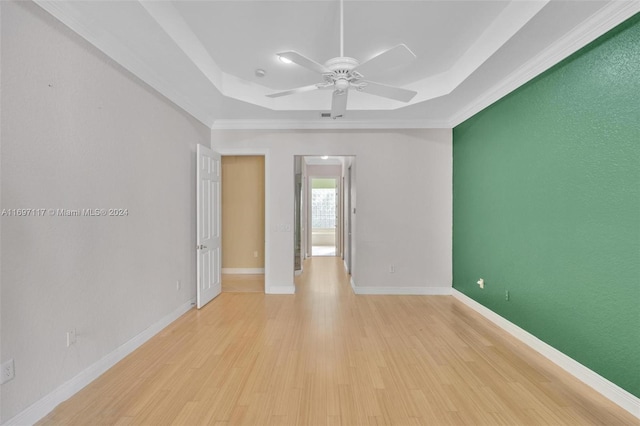 unfurnished room with ceiling fan, ornamental molding, a tray ceiling, and light hardwood / wood-style flooring