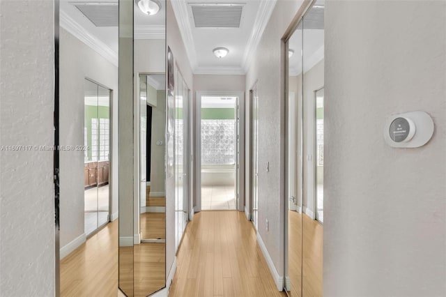 hall with light hardwood / wood-style floors and ornamental molding