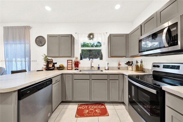 kitchen with kitchen peninsula, sink, gray cabinets, and appliances with stainless steel finishes