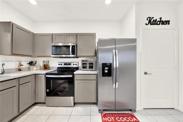 kitchen with gray cabinetry, light tile patterned flooring, and stainless steel appliances