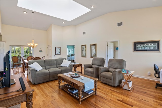 living room with a notable chandelier, light hardwood / wood-style flooring, high vaulted ceiling, and a skylight