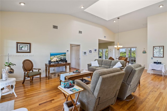 living room featuring high vaulted ceiling, light hardwood / wood-style floors, and an inviting chandelier