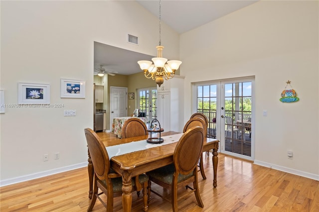 dining room featuring ceiling fan with notable chandelier, light hardwood / wood-style flooring, high vaulted ceiling, and french doors