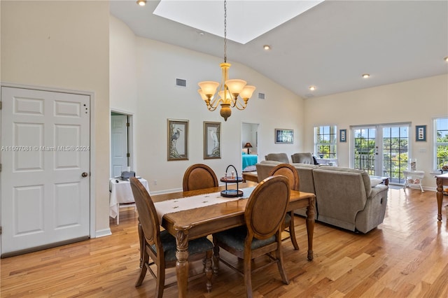 dining space featuring light hardwood / wood-style flooring, high vaulted ceiling, french doors, and a notable chandelier