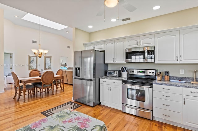 kitchen with a skylight, stainless steel appliances, light hardwood / wood-style flooring, white cabinets, and ceiling fan with notable chandelier