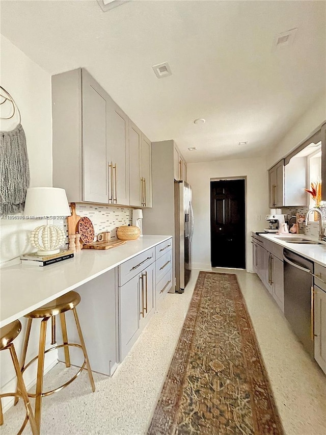 kitchen featuring a kitchen breakfast bar, stainless steel appliances, gray cabinetry, and sink