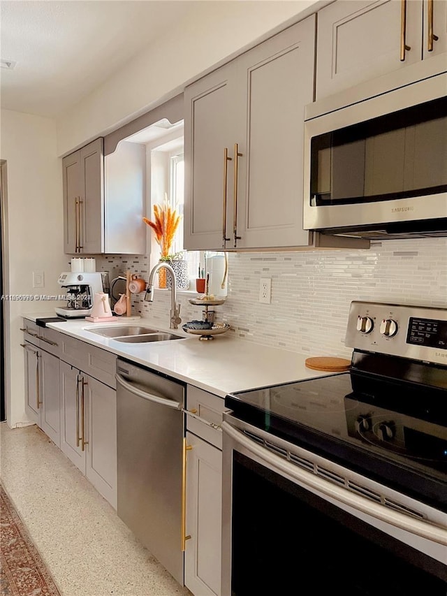 kitchen featuring gray cabinetry, backsplash, sink, and appliances with stainless steel finishes