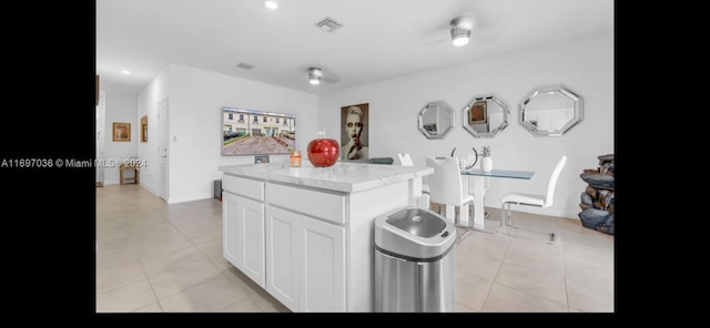 kitchen with a center island, light tile patterned flooring, and white cabinetry