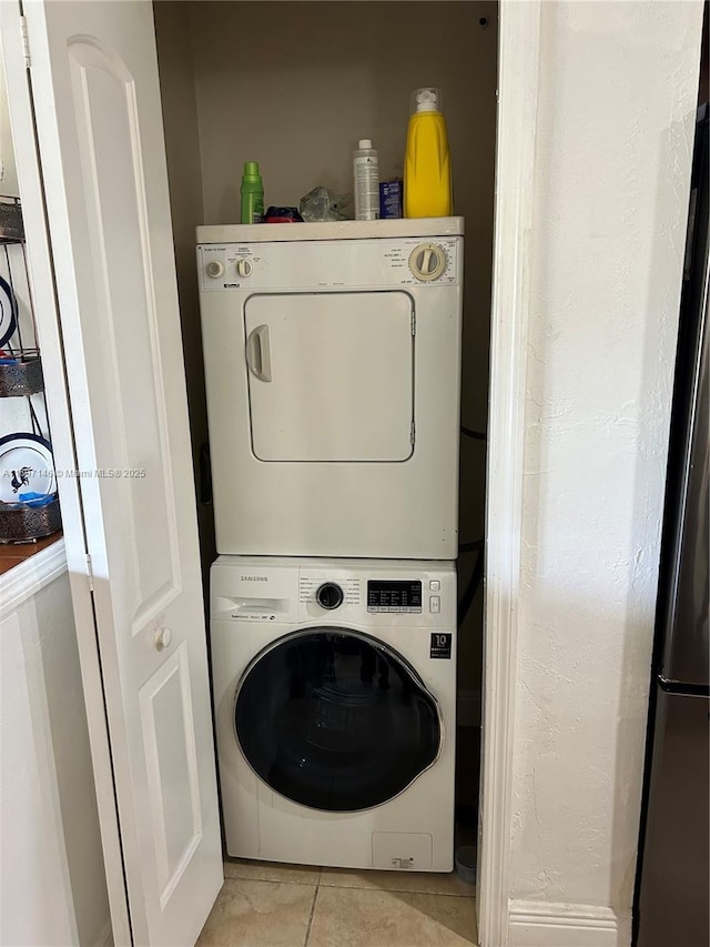 washroom featuring stacked washer / dryer and light tile patterned flooring