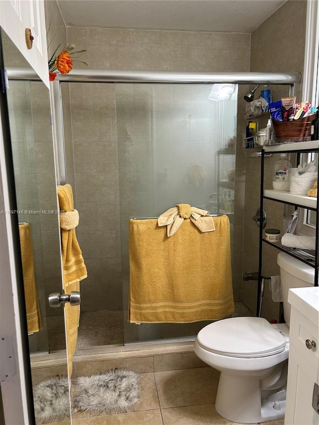 bathroom featuring tile patterned floors, vanity, toilet, and a shower with door