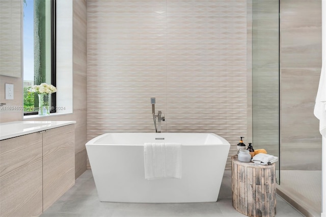 bathroom with a washtub, vanity, and tile walls