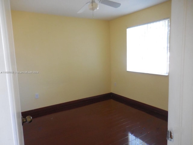 spare room featuring dark wood-type flooring, ceiling fan, and a healthy amount of sunlight