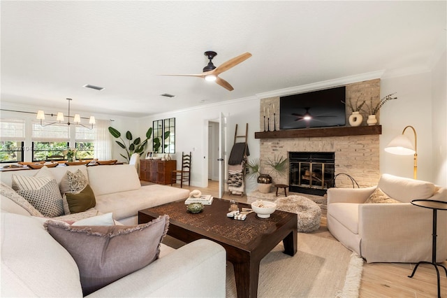 living room with a fireplace, ceiling fan with notable chandelier, light hardwood / wood-style flooring, and crown molding