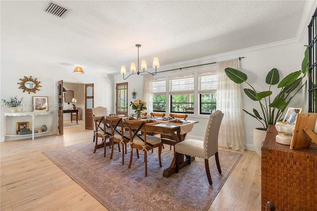 dining area with a chandelier, crown molding, light hardwood / wood-style floors, and a textured ceiling