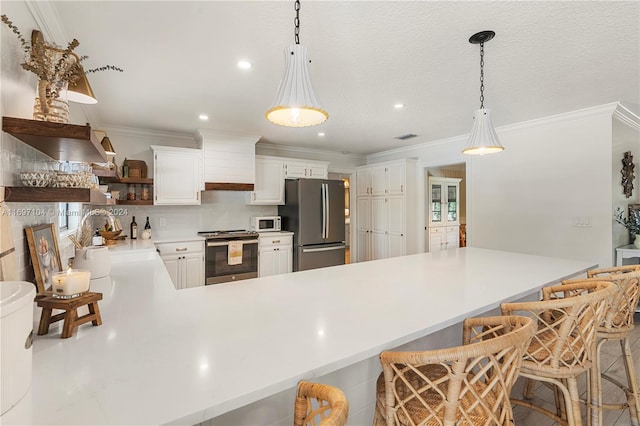 kitchen featuring a kitchen bar, stainless steel appliances, sink, white cabinetry, and hanging light fixtures