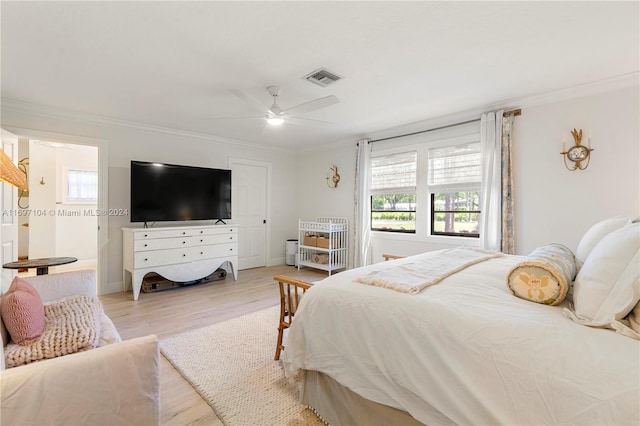 bedroom featuring light hardwood / wood-style flooring, ceiling fan, and ornamental molding