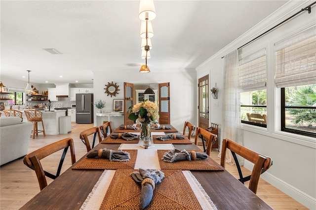 dining area featuring light wood-type flooring and crown molding