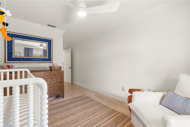 bedroom with ceiling fan, wood-type flooring, ornamental molding, and a nursery area