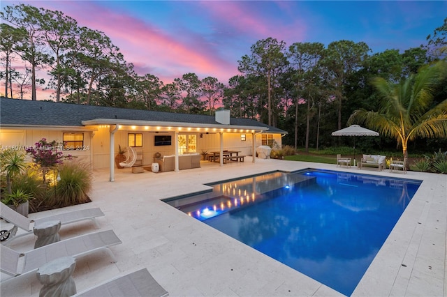 pool at dusk featuring outdoor lounge area and a patio area